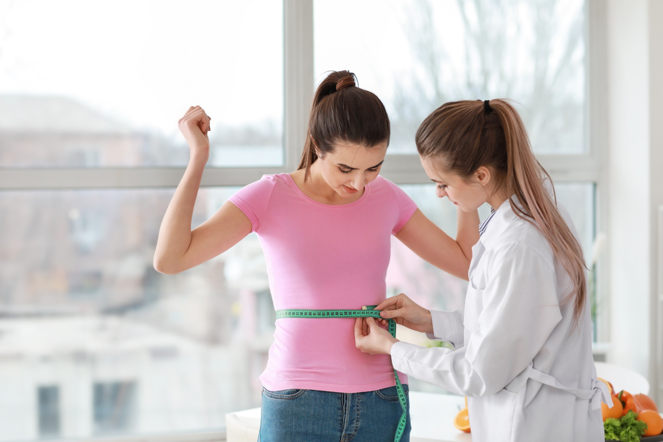 Nutritionist Measuring Waist of Young Woman in Weight Loss Clinic